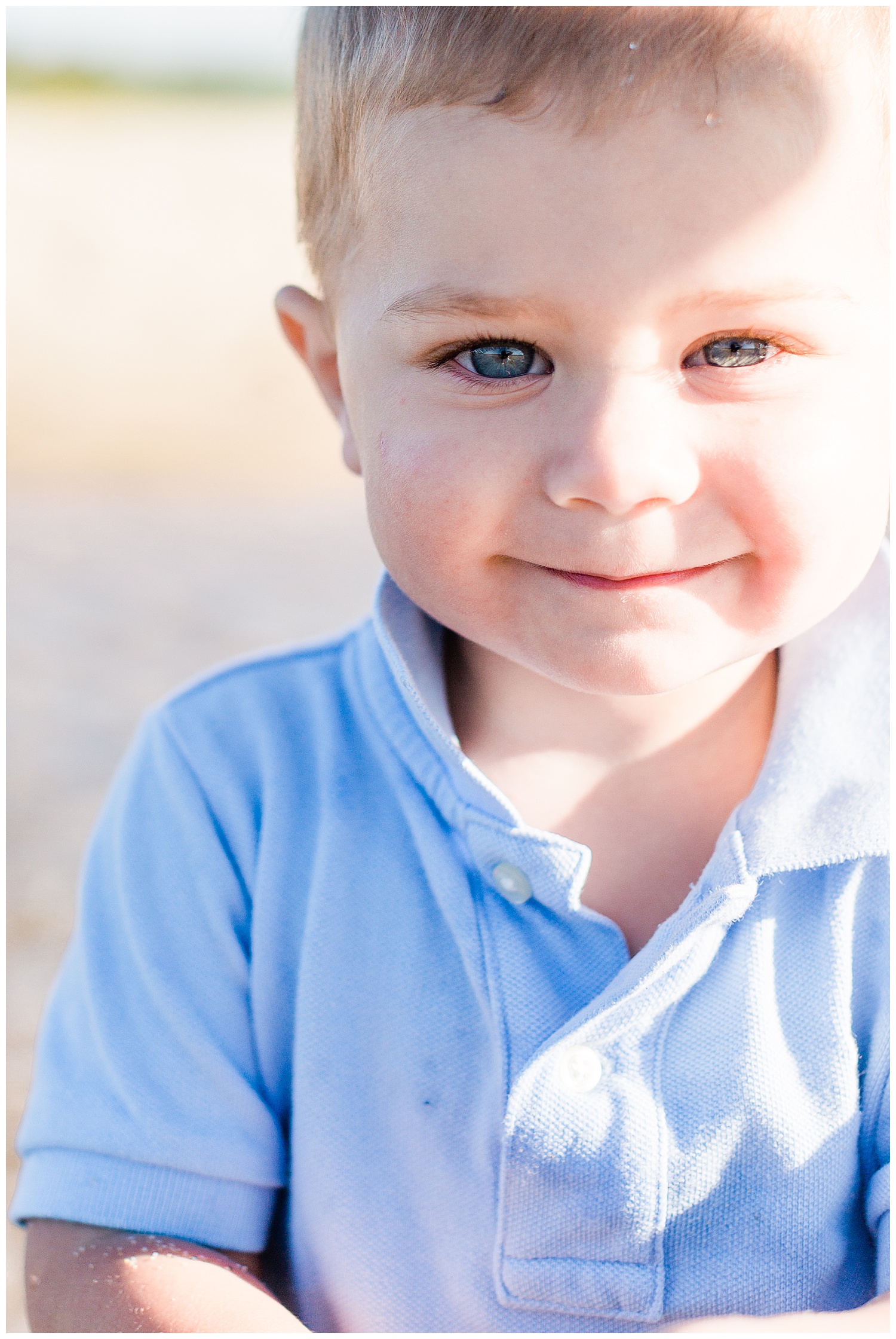 2 year old boy smiling at camera on beach