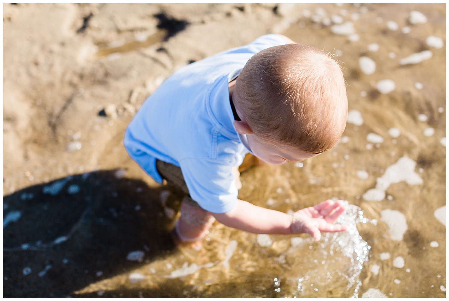 2 year old boy playing on beach in water