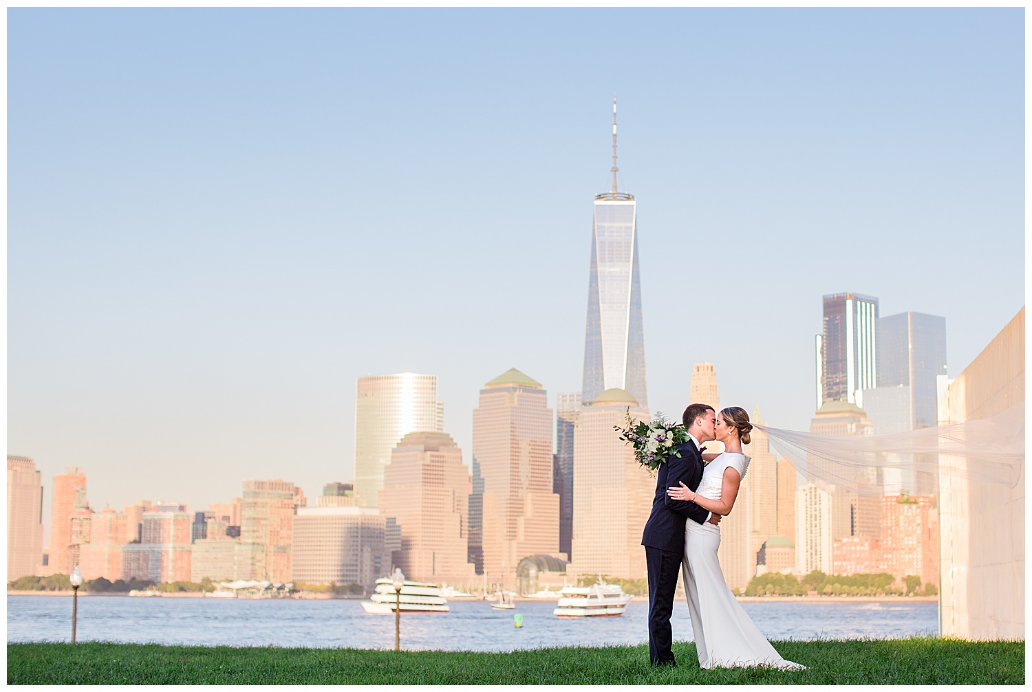 bride and groom kissing in front of New York City skyline at sunset