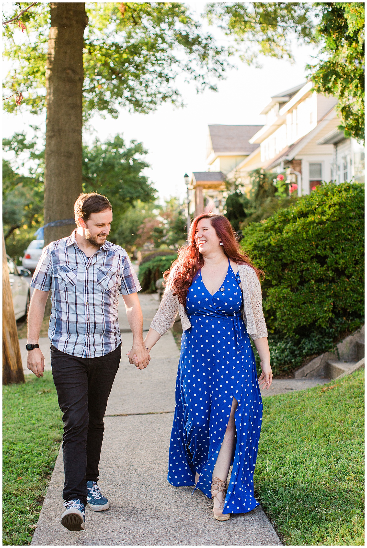 Couple holds hands while walking down sidewalk