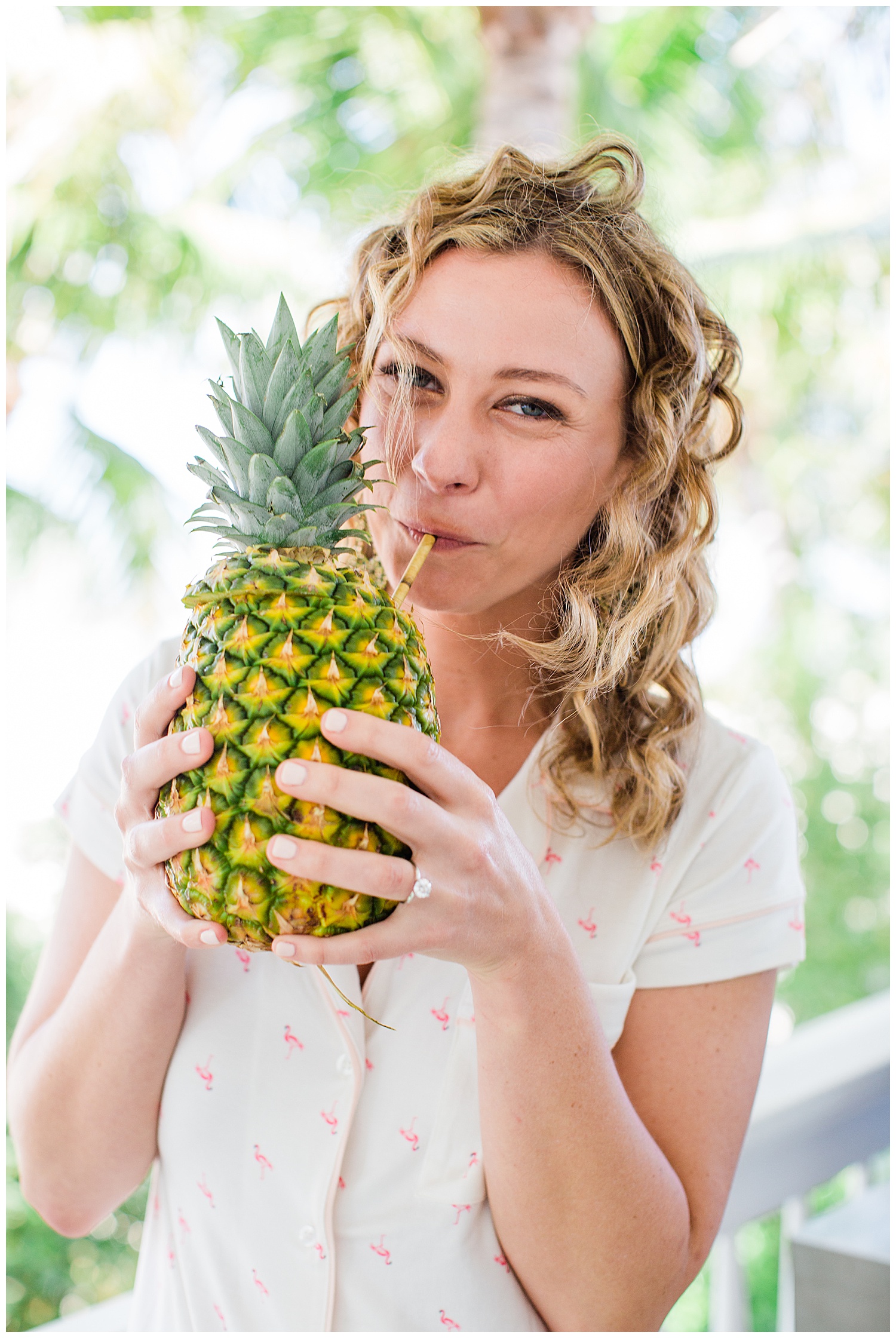 bride in pajamas drinking out of a pineapple before her wedding
