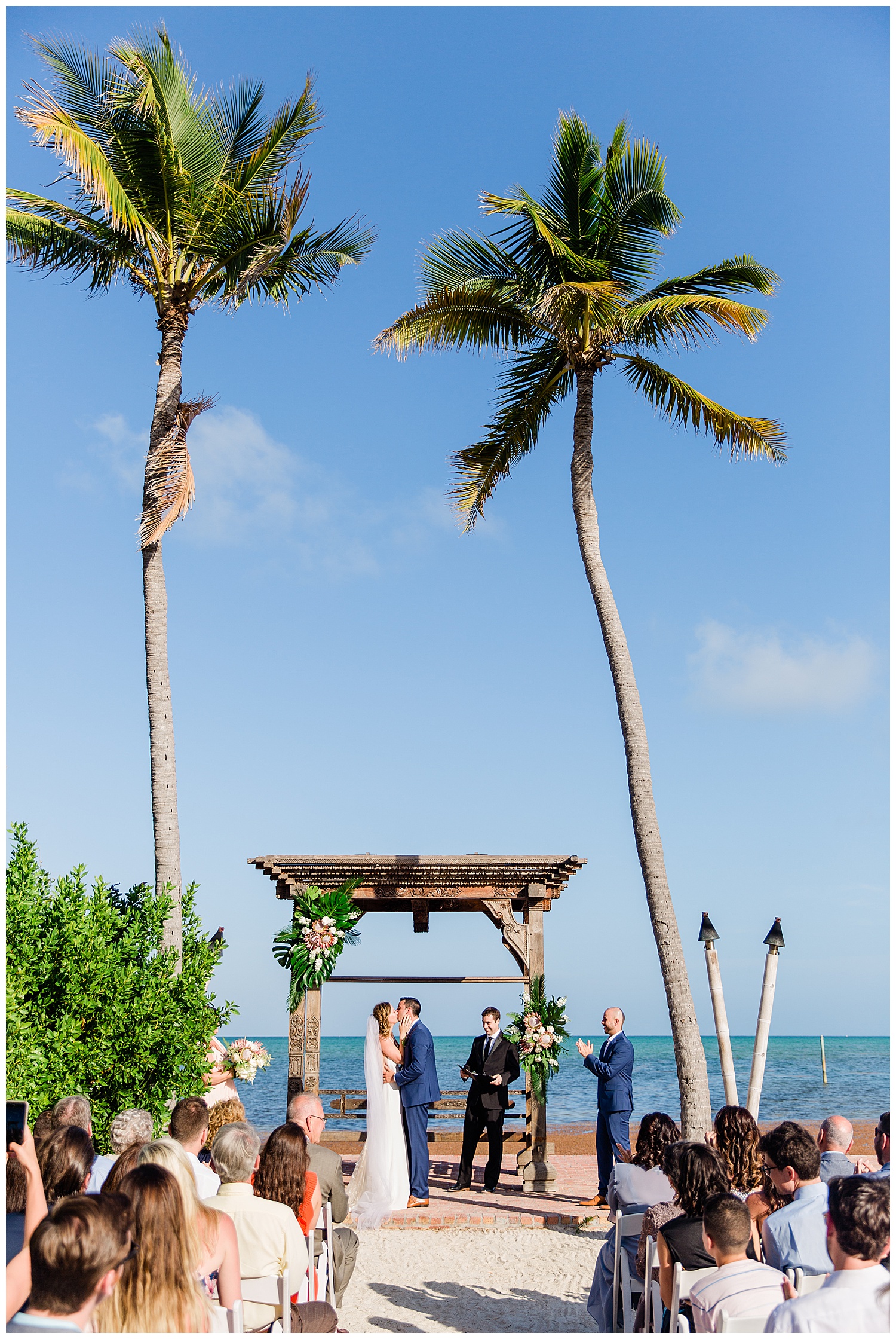 beach ceremony with wood altar surrounded by palm trees