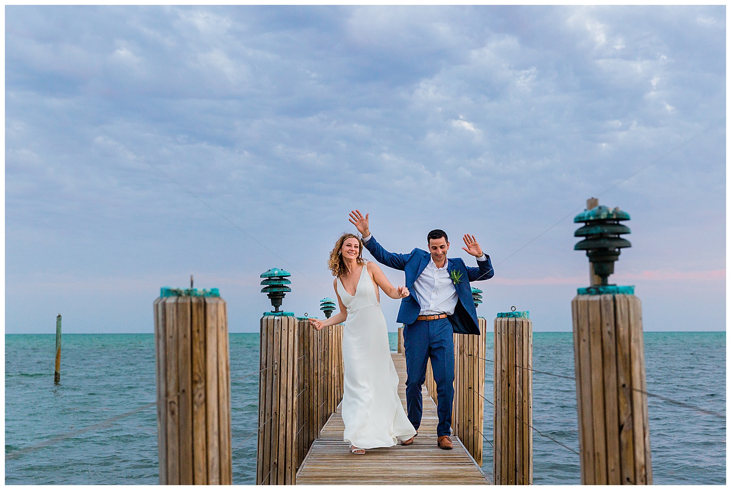 bride and groom dance on a dock on a blue ocean